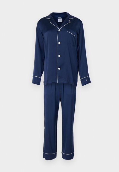 Navyblaue Schlafanzugset aus weichem Stoff, bestehend aus einem Hemd mit Knopfleiste, einer Tasche und weißem Piping sowie passenden Hosen mit geraden Beinen.