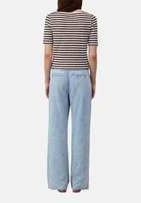 Haut à manches courtes rayé marron et blanc associé à un jean à jambes larges bleu clair avec poches arrière et coupe décontractée.