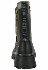 Stivale alla caviglia in pelle nera con zip laterale, superiore testurizzato, dettagli con logo e suola spessa e robusta. Accenti in metallo dorato presenti.