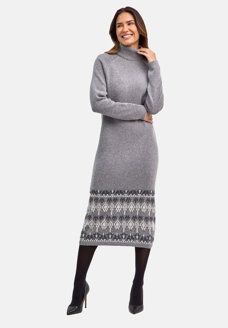 Langes, graues Strickkleid mit hohem Rollkragen, mit gemustertem Saum in dunklerem Grau und Weiß. Glatte Textur, figurbetonte Form.