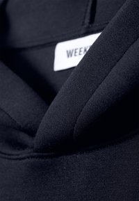 Sweatshirt bleu marine foncé avec une texture lisse, doté d'un col arrondi doux et d'une étiquette visible portant la mention "WEEKEND."