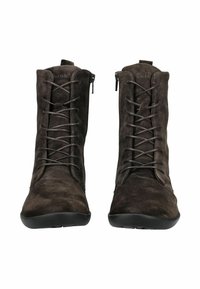 Un paio di stivaletti alla caviglia in suede marrone scuro con lacci, suole in gomma nera e cerniere laterali, visti frontalmente su uno sfondo bianco.