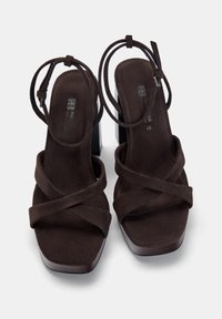 Brown suede high-heeled sandals with crisscross straps and square toe design. Features a thick block heel and minimal branding on the insole.