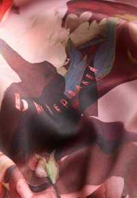 Material translucid cu modele abstracte florale vibrante; are un fundal întunecat cu accente roz și verzi și inscripția "baker".