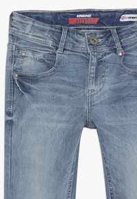 Jeans de mezclilla azul con un lavado desgastado, que cuentan con cinco bolsillos, un lazo para cinturón y una cinturilla con marca. Tejido elástico con detalles de costura visibles.