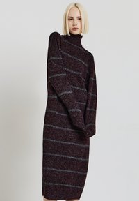 Abito a maglia bordeaux con strisce grigie, collo alto e maniche lunghe. Presenta un design snello e spacchi laterali per facilitare i movimenti.