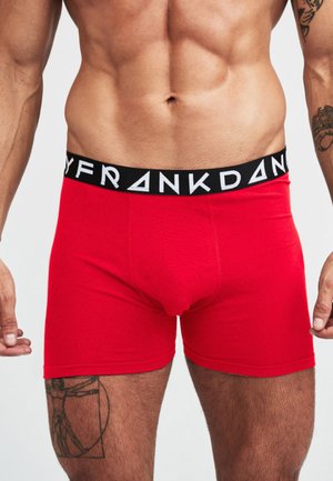 Röda bomullsboxershorts med ett svart elastiskt midjeband med texten "FRANK D." i vitt. Mjuk textur och åtsittande passform.