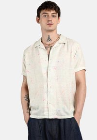 Camicia a maniche corte con bottoni in tessuto leggero e finitura testurizzata, caratterizzata da motivi astratti colorati in rosa, blu e verde.