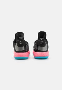 Zapatillas Nike negras con suelas rosas y azules. Cuentan con una textura suave, un collar acolchado y un acento reflectante en plata en el lateral.