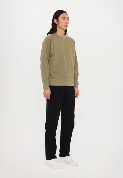 Oliven grøn sweatshirt med raglanærmer, ribbede manchetter og kant; parret med sorte sweatpants og hvide sneakers; ensartet design.