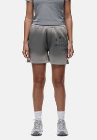 Pantaloni corti grigi in misto cotone con vita regolabile, caratterizzati da un effetto sbiadito e testo stampato in grigio scuro. Abbinati a una t-shirt grigia coordinata.