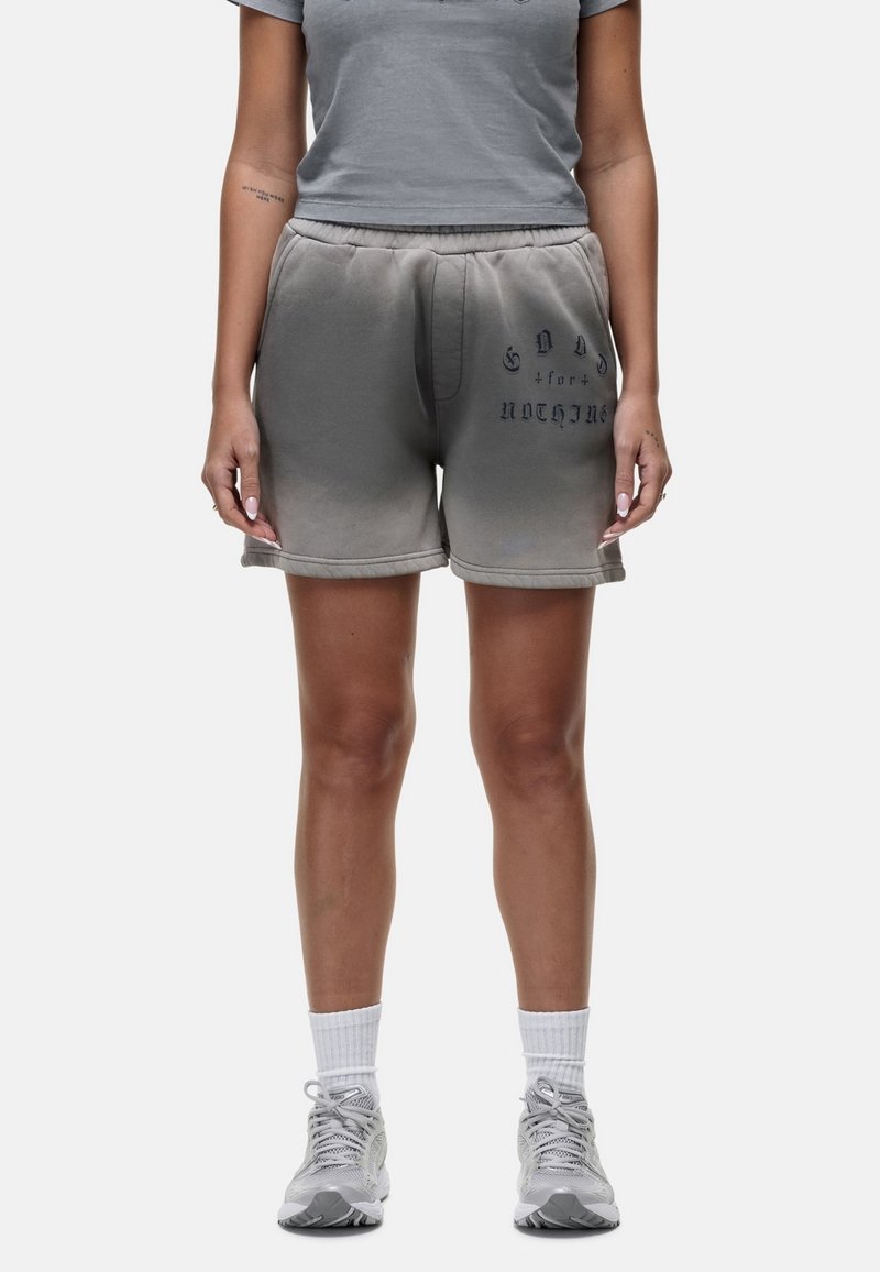 Pantaloni corti grigi in misto cotone con vita regolabile, caratterizzati da un effetto sbiadito e testo stampato in grigio scuro. Abbinati a una t-shirt grigia coordinata.