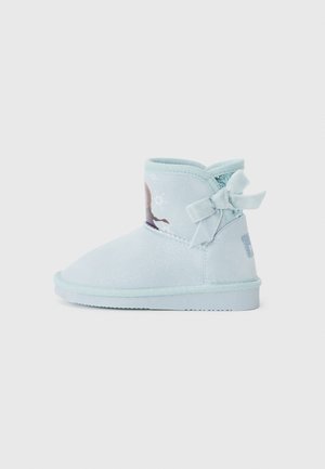 Bottes chelsea bleu clair en matériau doux, avec une finition scintillante, un nœud décoratif à l'arrière et une image sur le côté.