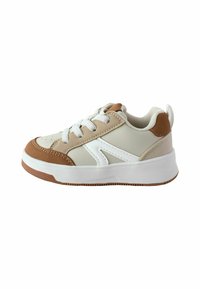 Des baskets avec une tige en synthétique beige et marron, des accents blancs, un bout rond, un laçage et une semelle en caoutchouc blanche avec des crampons marron.