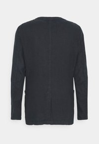 Camicia a maniche lunghe di lino di un blu scuro, con un semplice scollo rotondo, tasche laterali e una linea dritta con dettagli di cucitura minimi.