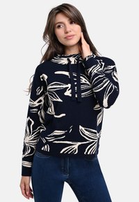 Marineblauer gestrickter Pullover mit einem weißen Blumenmuster, mit Kapuze und Kordelzügen, langen Ärmeln und einer lockeren Passform. Strukturierte Oberfläche.