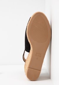 Sorte ruskinds wedgesandaler med en vævet jute hæl, gummisål og præget mærkenavn. Sålen har et struktureret grip-mønster.