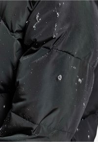 Vandafvisende sort dunjakke med en kviltet design, der viser dråber af vand på overfladen og demonstrerer dets vejrbestandige materiale.