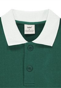 Grønn poloshirt med hvit ribbestrikket krage, to mørke knapper og en glatt tekstur. Inneholder en etikett som angir materialer og størrelse.