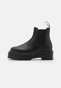 Boots Chelsea negre din piele netedă, cu panouri laterale elastice, având o talpă groasă, texturată și o bandă de tragere în partea din spate.