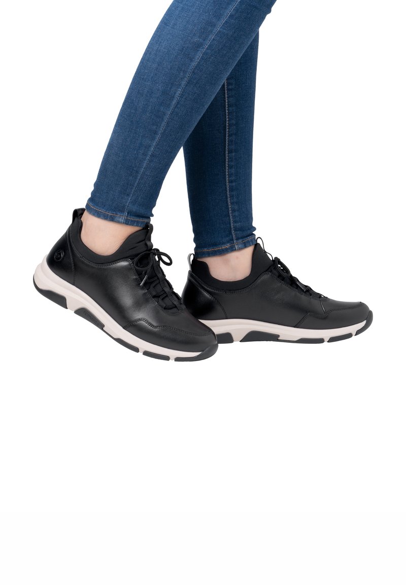 Black leather sneakers with a low profile, textured finish, and a white sole featuring black accents. Laces and padded collar are included.