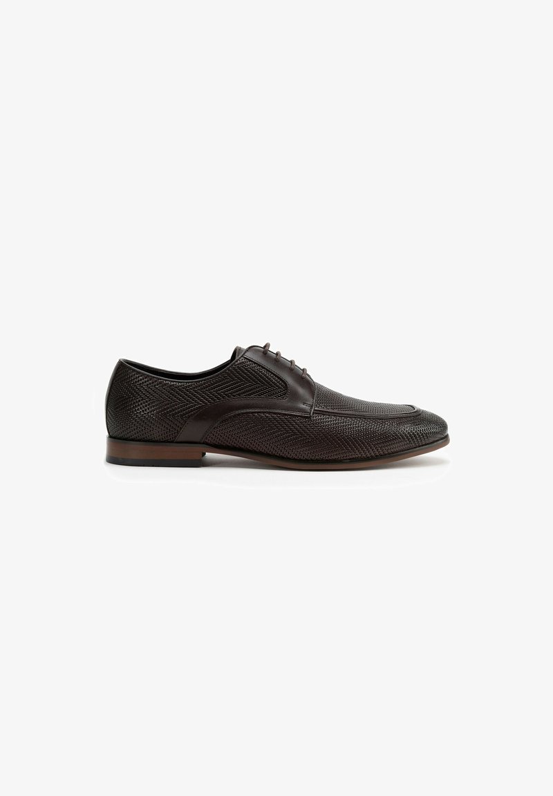Chaussure habillée en cuir brun avec un extérieur texturé, dotée d'un bout arrondi et de détails de couture subtils. Design à lacets et talon bas.