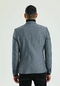 Grauer Blazer mit strukturierter Oberfläche, tailliertem Design und kontrastierendem schwarzen Kragen. Verfügt über geknöpfte Manschetten und eine elegante, maßgeschneiderte Silhouette.