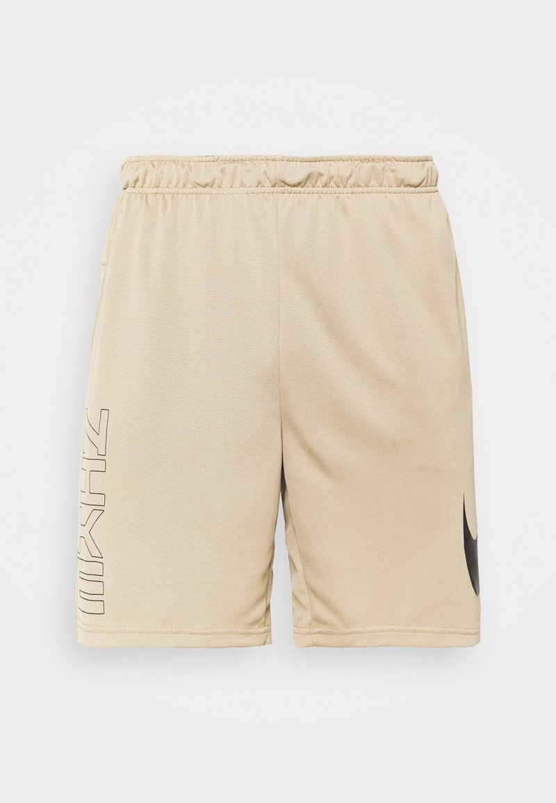 Short de sport beige avec bande élastique à la taille, logo Nike noir sur la jambe droite et texte vertical noir contouré sur la jambe gauche.