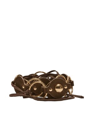 Rjav usnjen pas z zlatimi okroglimi kovinskimi poudarki in tankim usnjenim trakom, zvit na belem ozadju.