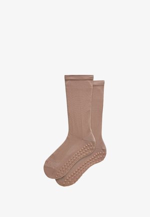 Paar beige antislip sokken met een gemarmerde grip op de zolen, lengte tot halverwege het kuit, gebreide stof ontworpen voor stabiliteit en comfort.