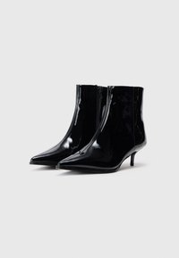 Botas de salto baixo de pele pretas envernizadas com biqueira pontiaguda e fecho de correr lateral, apresentando um acabamento liso e brilhante.