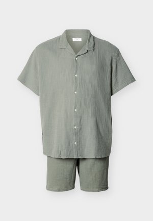 Hele-rohelise lühikeste varrukatega särgi ja sobivate põlveni ulatuvate lühikeste pükstega komplekt, mõlemad valmistatud tekstuurse, kortsulise kangast.