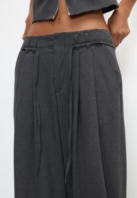 Grijze op maat gemaakte broek met een losse pasvorm, geplooide voorkant, verstelbare trekkoord taille en zijzakken. Soepele textuur, minimalistisch ontwerp.