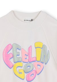 Sweatshirt blanc avec un grand graphisme "Feelin' Good" en lettres multicolores et scintillantes. Col en rib et manches raglan.