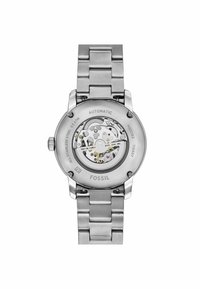 Automatische Armbanduhr aus Edelstahl mit silberner Optik, ausgestattet mit einem transparenten Gehäuseboden, der feine mechanische Details und die Bewegung zeigt.
