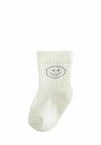 Weiße gerippte Kindersocke mit einer grauen Smiley-Gesicht-Illustration am äußeren Knöchel, ausgestattet mit einer weichen Textur und einem umgeschlagenen Bündchen.