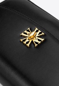 Portafoglio in pelle nera con un emblema metallico dorato in rilievo, dotato di dettagli intricati e una superficie liscia.