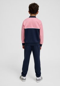 Chándal con una combinación de colores rosa y marino, que incluye una chaqueta con cremallera, puños elásticos y pantalones a juego. Fabricado con tela suave.