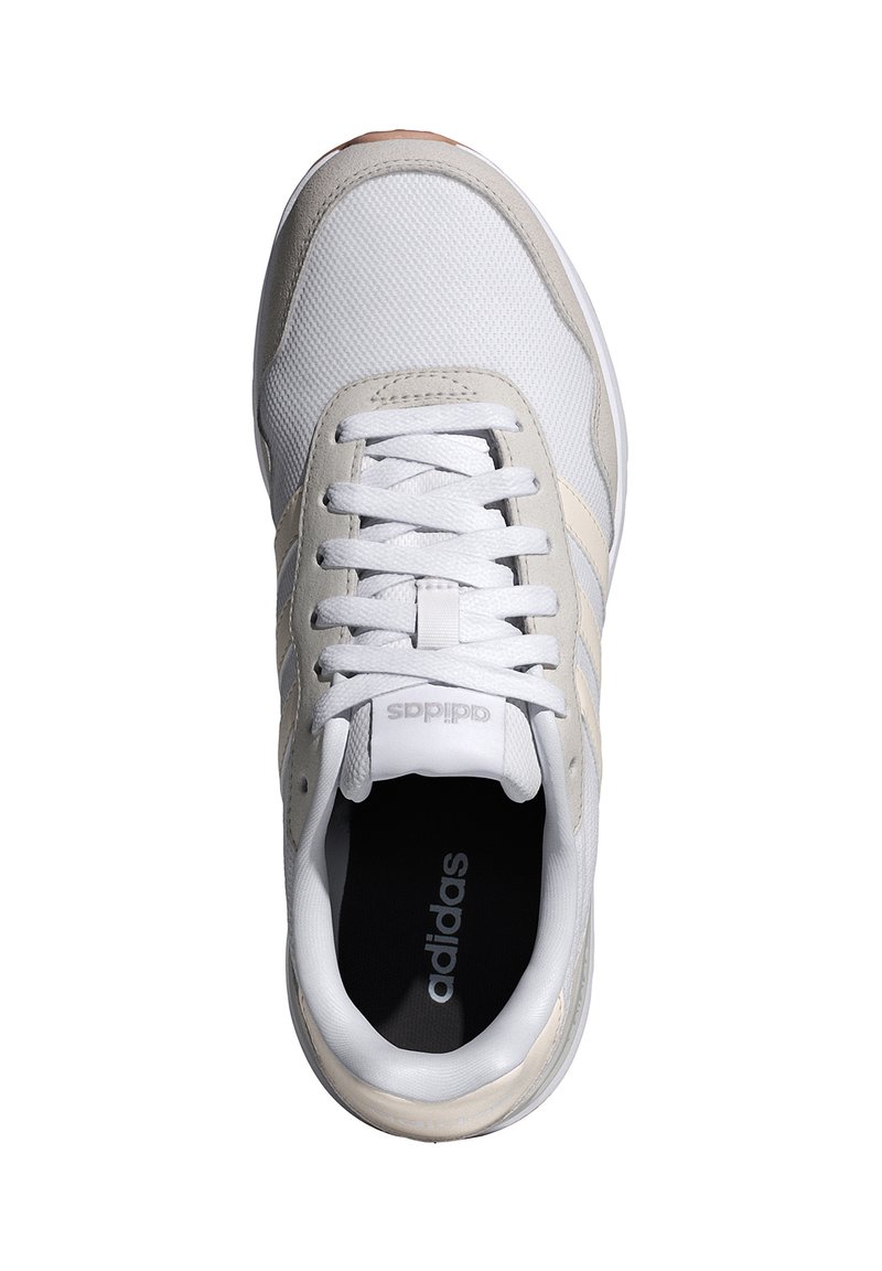 Zapatilla blanca con parte superior de malla y piel; presenta acentos en beige, cordones planos y una suela de goma. El interior muestra una plantilla negra con el logotipo.