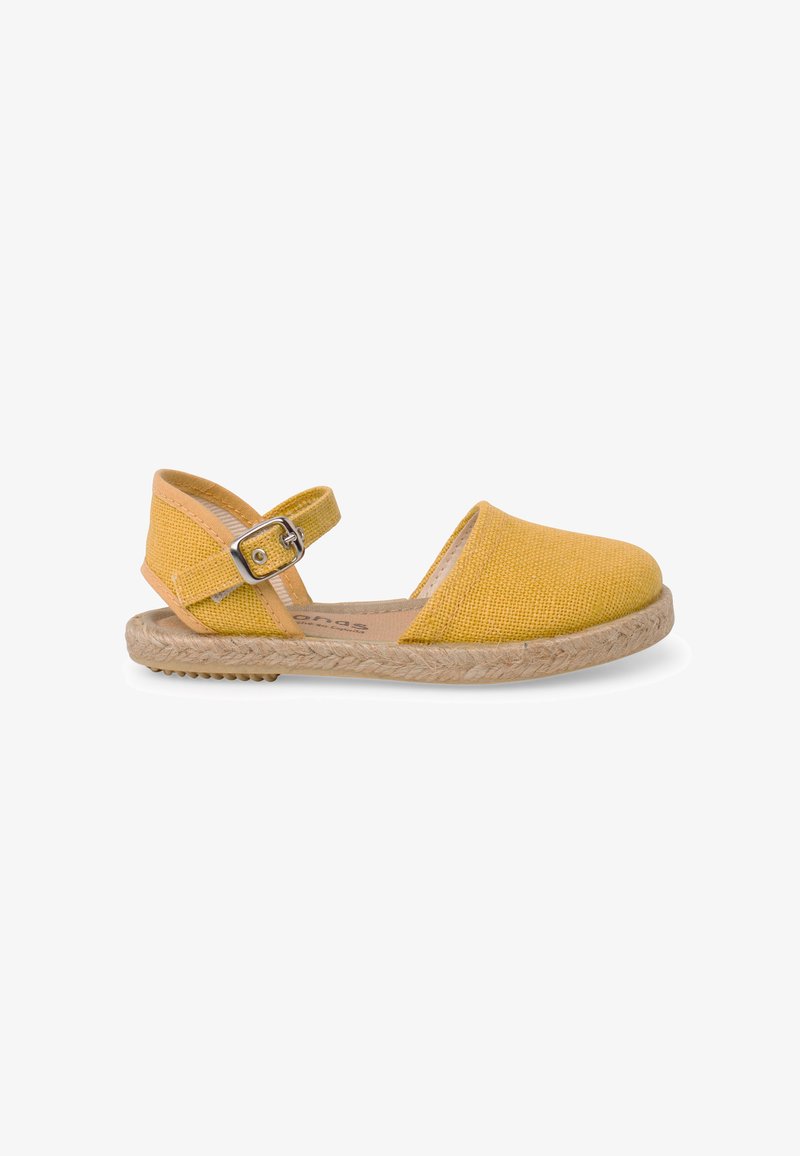 Sandale espadrille jaune à bout fermé avec bride à la cheville, boucle métallique et semelle en jute texturée sur fond blanc.