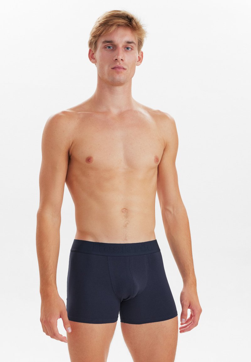 Marineblå boxershorts lavet af strækstof med en blød elastisk talje, der viser et diskret præget logo, tætsiddende design og længde til midt på låret.