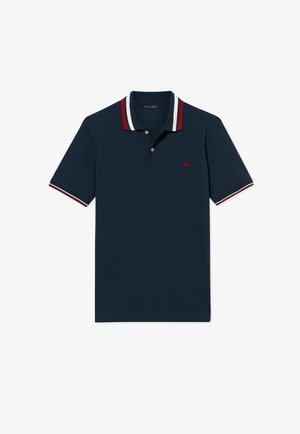 Marineblaues kurzärmliges Poloshirt mit rot-weiß-marineblau gestreiftem Kragen und Ärmelabschlüssen und kleinem roten Sticklogo auf der Brust.