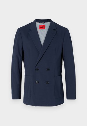 Blazer azul-marinho de dupla abotoadura com lapela cortada, dois bolsos frontais e botões pretos. O interior apresenta um forro azul claro.