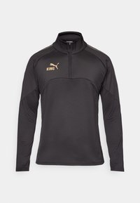 Suéter negro de manga larga con cuello alto, presentando un logo dorado en el pecho y acentos grises en los hombros. Material textil suave.