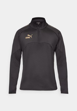 Zwarte pullover met lange mouwen en een hoge kraag, voorzien van een gouden logo op de borst en grijze accenten op de schouders. Glad textielmateriaal.