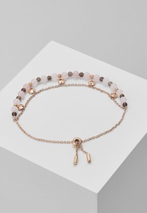 Bracelet délicat avec des perles alternées roses, blanches et grises, chaîne en or rose et fermoir réglable avec deux extrémités pendantes.