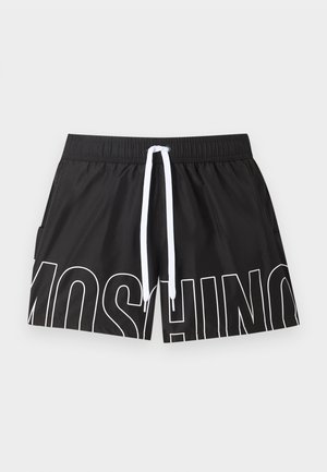 Mustat uimashortsit, joissa valkoinen säädettävä nyöritys ja suuret valkoiset ääriviivat, jotka muodostavat sanan "MOSCHINO" edessä.