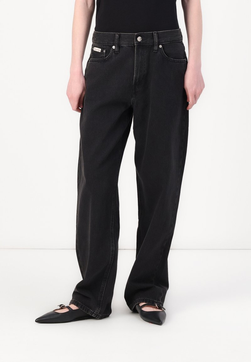 Black denim wide-leg jeans with a high waist, featuring front pockets, a button fly, and a subtle brand tag on the waistband.