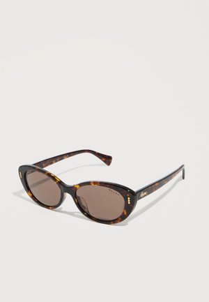 Lunettes de soleil œil de chat en écaille de tortue avec des verres marron et des accents subtils dorés et blancs sur la monture.