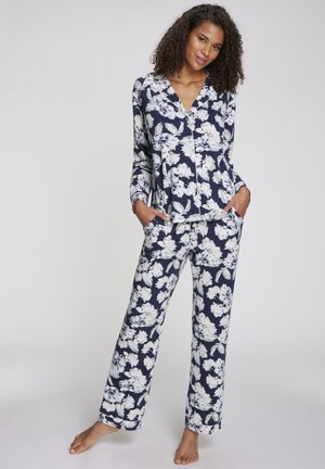 Pajama set s cvjetnim uzorkom na tamnoplavoj podlozi s velikim bijelim i zelenim cvjetovima, dugih rukava, s košuljom s kragnom i širokim hlačama.